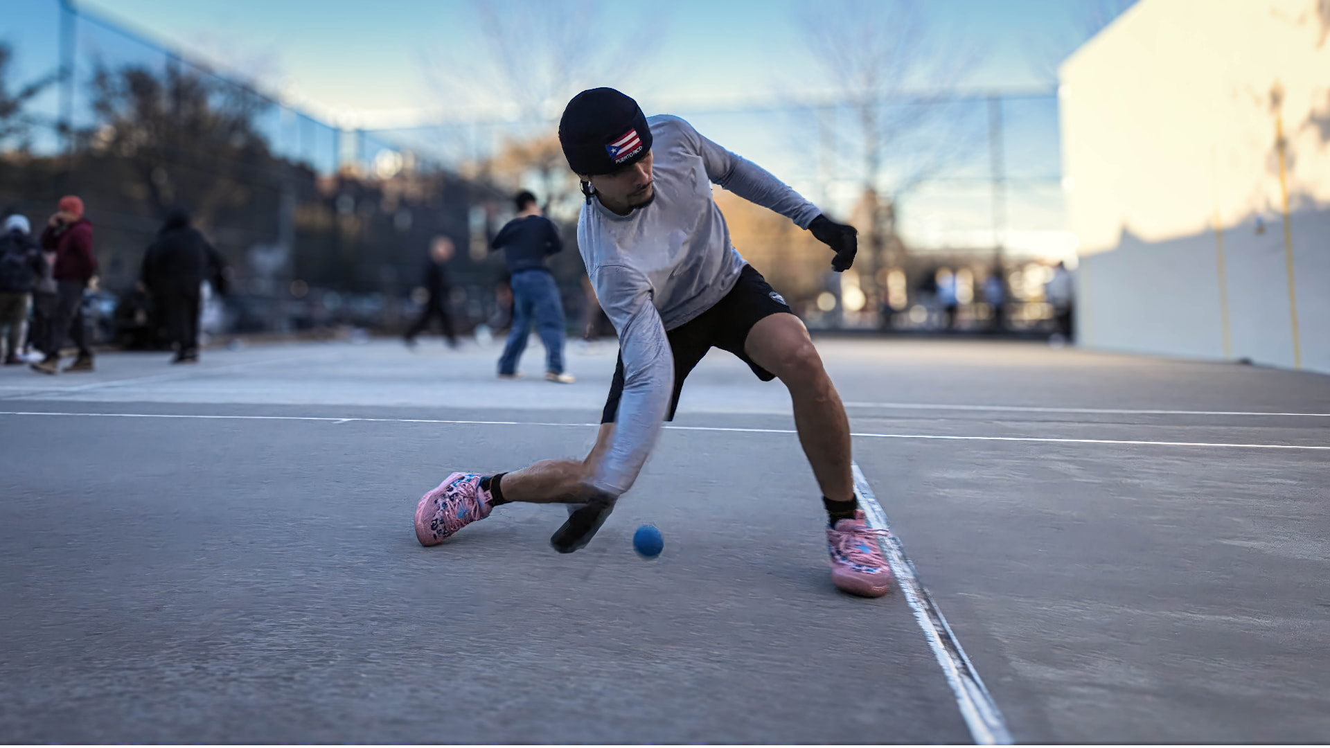 A MegaWall player lunging low to scoop the ball during an outdoor one-wall match